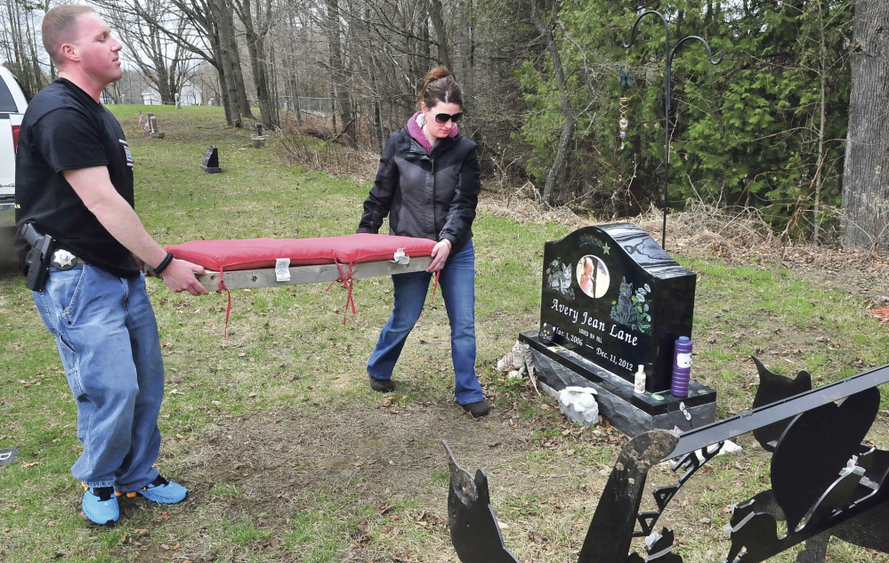 Kennebec County sheriff’s Deputy Jacob Pierce and Tabitha Souzer on Tuesday return a cushion to the bench that was thrown down an embankment near the grave site of Souzer’s daughter, Avery Lane, in the Friends Cemetery in Fairfield.