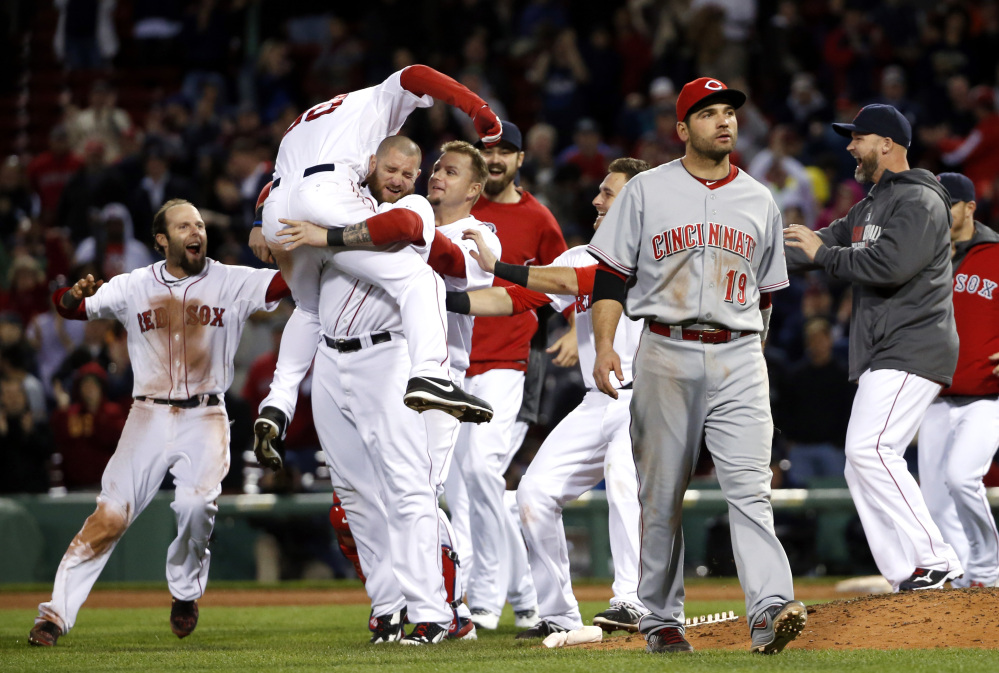 Boston Red Sox center fielder Grady Sizemore (38) jumps into the arms of teammate Jonny Gomes as he and teammates celebrate his walk-off single to defeat the Cincinnati Reds 4-3 in the 12th inning of a baseball game at Fenway Park in Boston, Tuesday, May 6, 2014. Reds first baseman Joey Votto (19) walks off the field.