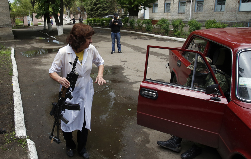 A nurse holds a gun as she helps a wounded pro-Russian gunman out of a car in front of a hospital in Slovyansk, eastern Ukraine, on Monday.