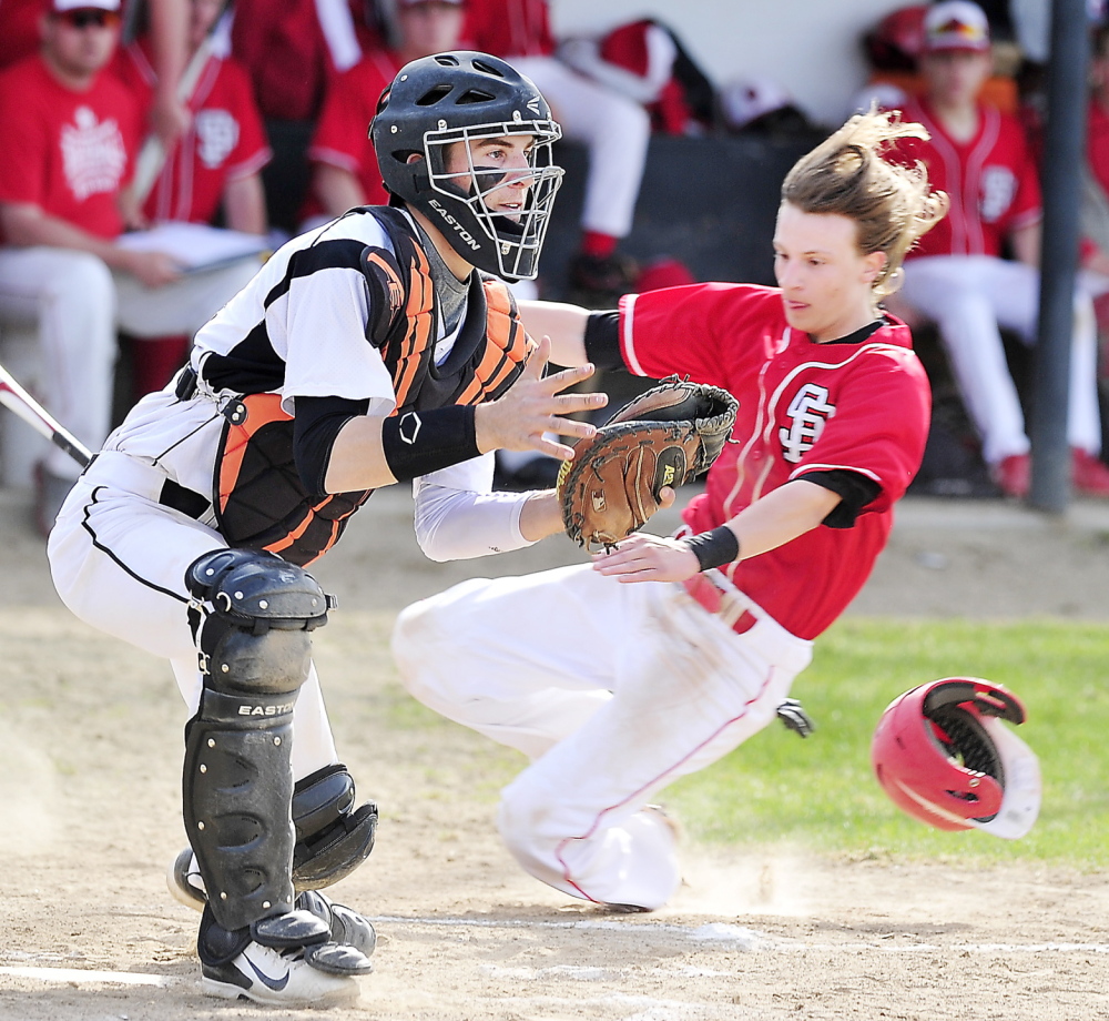 Cosmo Romano of South Portland slides across the plate as Biddeford catcher Corey Brown waits for a throw from center field during their SMAA game at Biddeford.