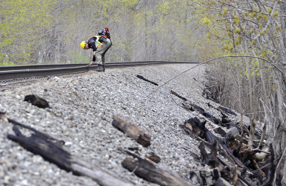 Maine Forest Ranger Matthew Bennett looks for evidence Friday that a train caused a fire along train tracks in Saco on Thursday. Some witnesses report seeing sparks shooting from a freight train, while others say they saw a swirl of burning leaves and debris in the air.