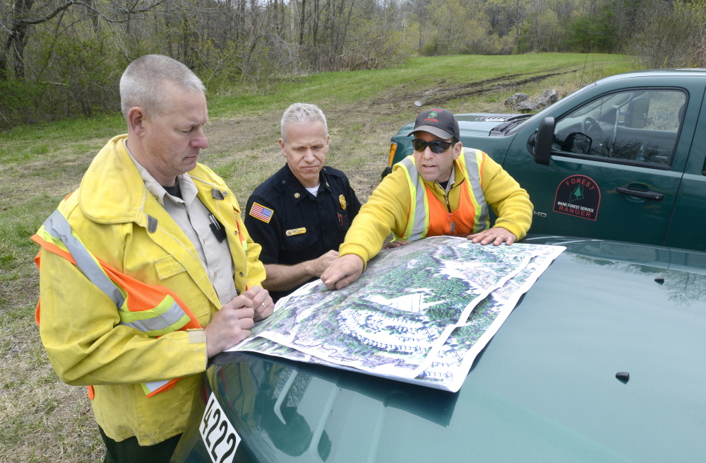 Old Orchard Beach, ME - MAY 9: Maine Forest Rangers Mark Rousseau (left) and John Leavitt (right) are joined by Saco Fire Dept. deputy chief Robert Martin in going over a map as they assess fire damage along the train tracks in Saco. (Photo by John Patriquin/Staff Photographer)