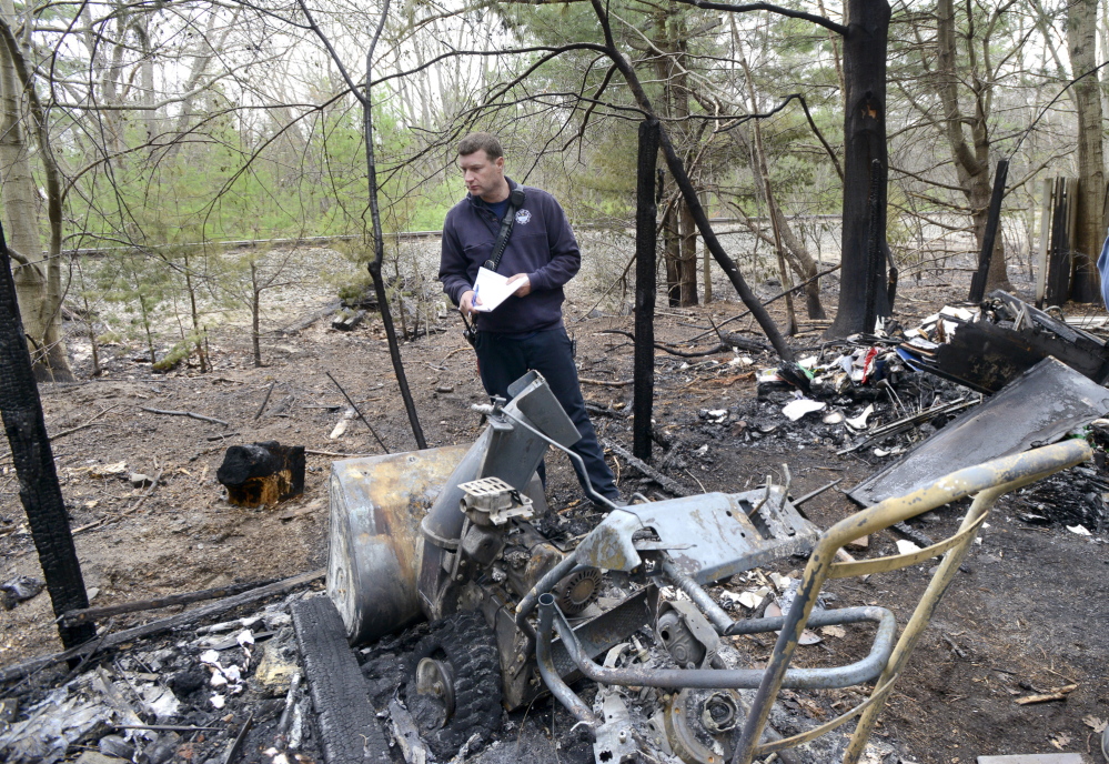 Old Orchard Beach, ME - MAY 9: Old Orchard Beach Fire Dept. Captain Brett Jones takes notes of a destroyed snowblower shed next to a condo complex on Old Salt rd. in OOB as he and other officials assess fire damage along the train tracks in the background.. (Photo by John Patriquin/Staff Photographer)