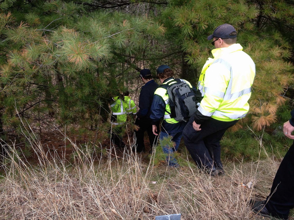 Searchers looking for Jaden Dremsa walk down a steep bank into the woods along Route 5 in North Waterboro on Friday.