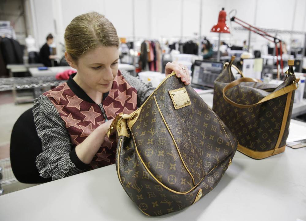 Jenna Starr inspects a pair of Louis Vuitton handbags to authenticate them and make sure they meet brand standards at the headquarters of The RealReal in San Francisco.