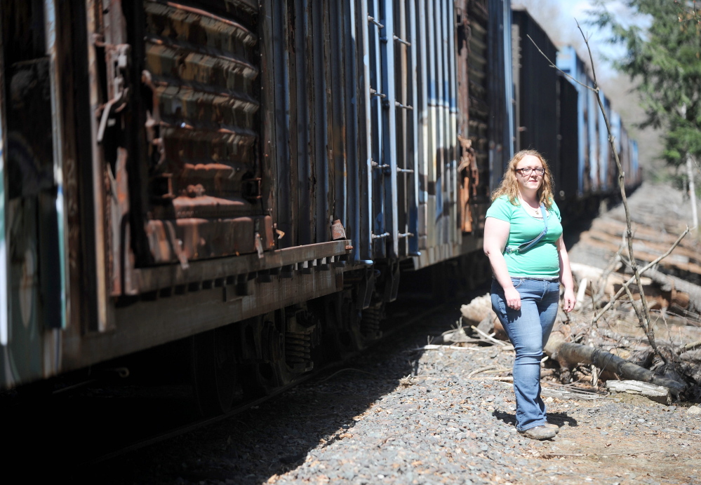 Miriam Easton stands beside a neglected train on tracks that run through her family’s 80-acre property Thursday in Oakland.