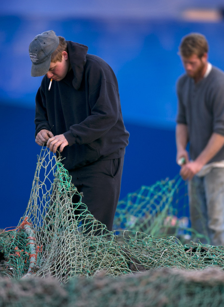 Fishermen Ed Stewart, left, and Tannis Goodsen mend groundfishing nets on Merrill Wharf in Portland last year.