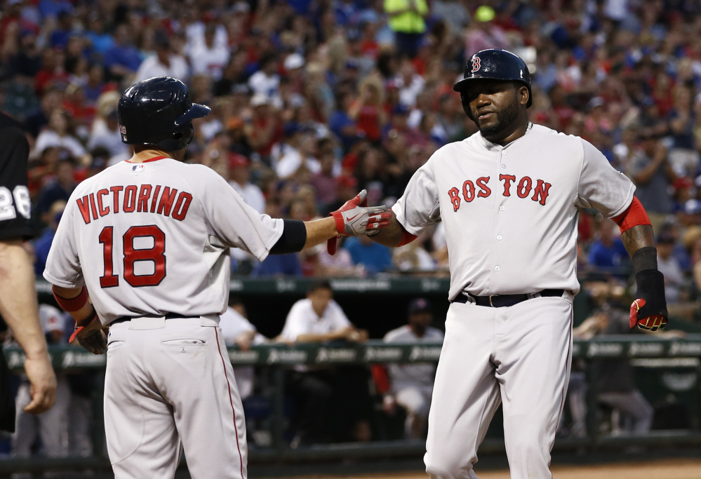 Red Sox designated hitter David Ortiz, right, and outfielder Shane Victorino congratulate each other after scoring on a hit by Jonny Gomes in the fourth inning of Saturday’s game against the Texas Rangers in Arlington, Texas.