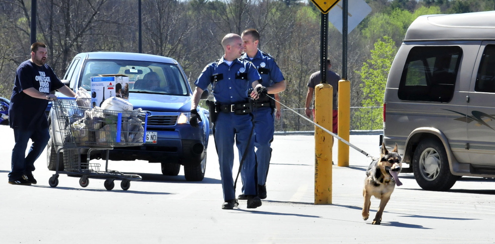 Two state troopers and a tracking dog search vehicles in the Walmart parking lot after two people said they were robbed while making a deposit at the nearby Bangor Savings Bank in Waterville on Sunday, May 11, 2014.