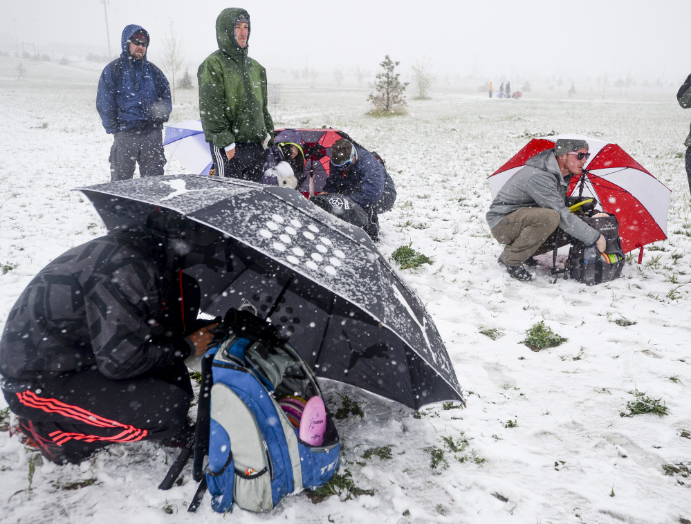 Disc Golf players shield themselves from the snow and wind with umbrellas as they compete in a tournament Sunday in Fort Collins, Colo. Snow is expected to fall through Monday, with highs reaching the 60s later this week.