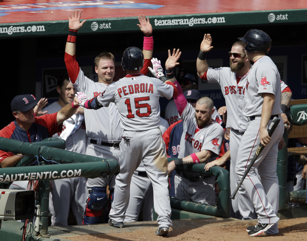 Boston’s Dustin Pedroia is congratulated by Manager John Farrell, left, catcher A.J. Pierzynski and Mike Napoli, second from right, following his solo home run off Robbie Ross of the Rangers in the seventh inning Sunday.