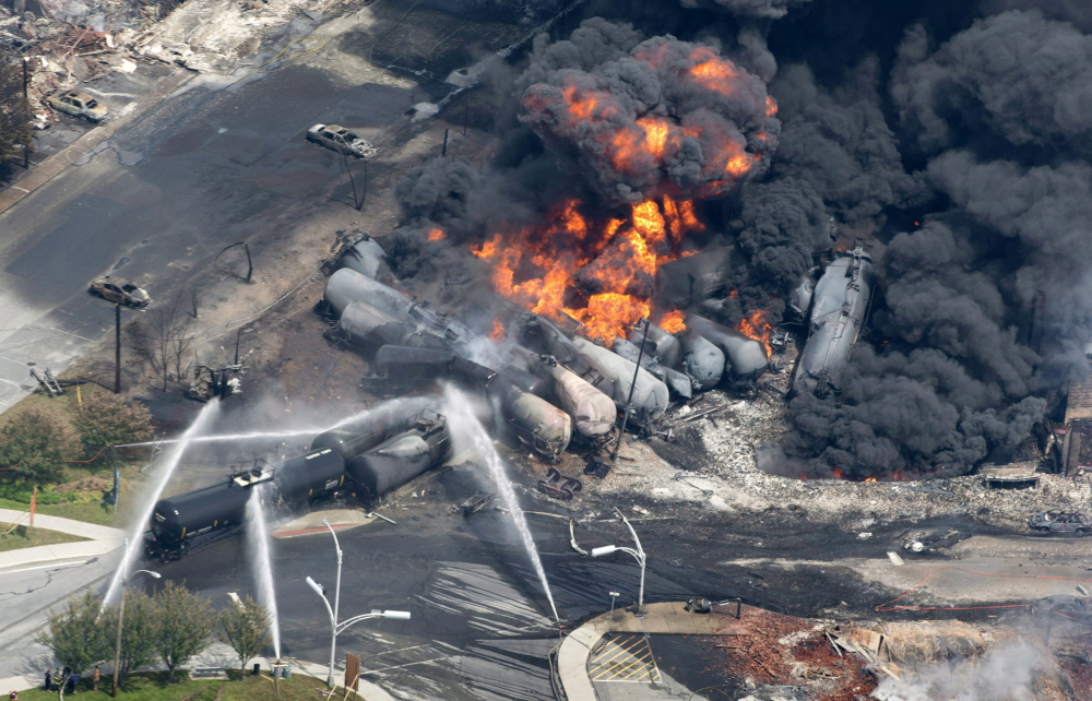 This July 6, 2013, file photo shows smoke rising from railway cars that were carrying crude oil after derailing in downtown Lac-Megantic, Quebec. The tragedy occurred when a runaway train carrying 72 carloads of crude oil derailed, hurtled down an incline and slammed into downtown Lac-Megantic. Several train cars exploded, 40 buildings were leveled and 47 people were killed.