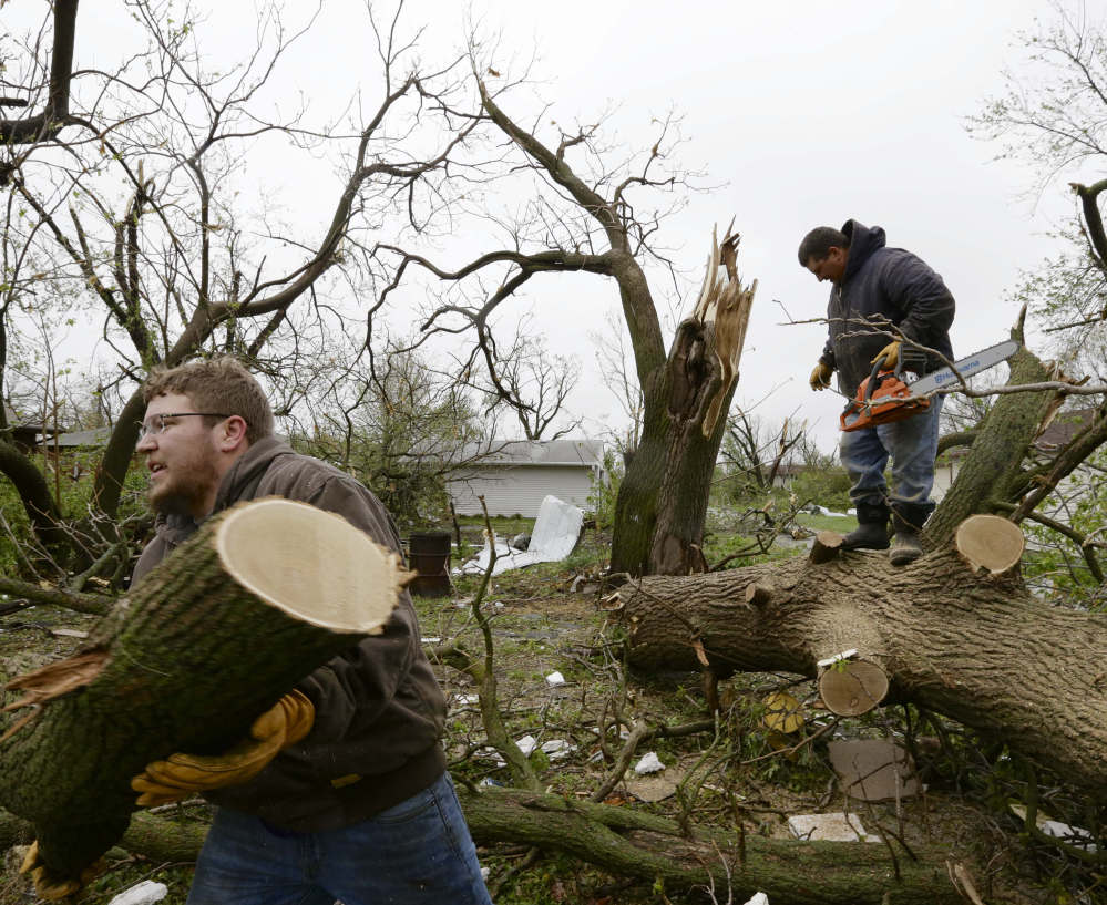 Adam Pankoke, left, and Nick Streit clear fallen trees Monday in Beaver Crossing, Neb., which was hit hard when several tornadoes moved across the state Sunday.