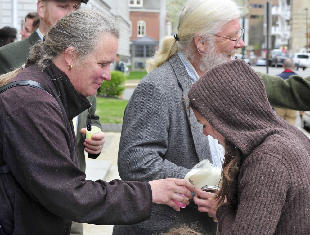 Angie Wollmar of Sedgwick, whose family owns New Mooring Farm, gets a cup of raw milk from Bridget McKeen of New Montville after a demonstration against federal intervention in town ordinances before the Maine Supreme Judicial Court hears the case of farmer Dan Brown on Tuesday.