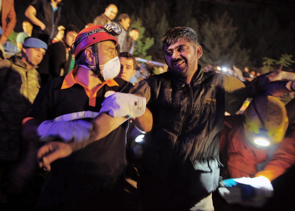 Miners help a rescued friend hours after an explosion and fire at a coal mine killed dozens and trapped others in Soma, in western Turkey, on Tuesday.