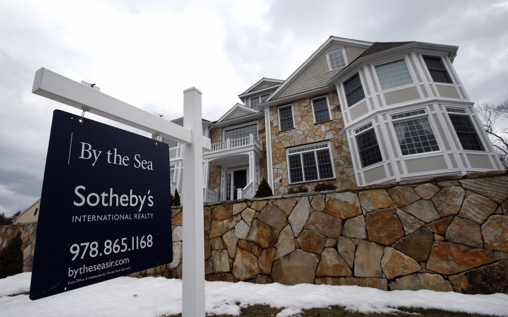 A for sale sign hangs at a home in North Andover, Mass. The top regulator of Freddie Mac and Fannie Mae is abandoning his predecessor’s plan to scale down their housing market roles.