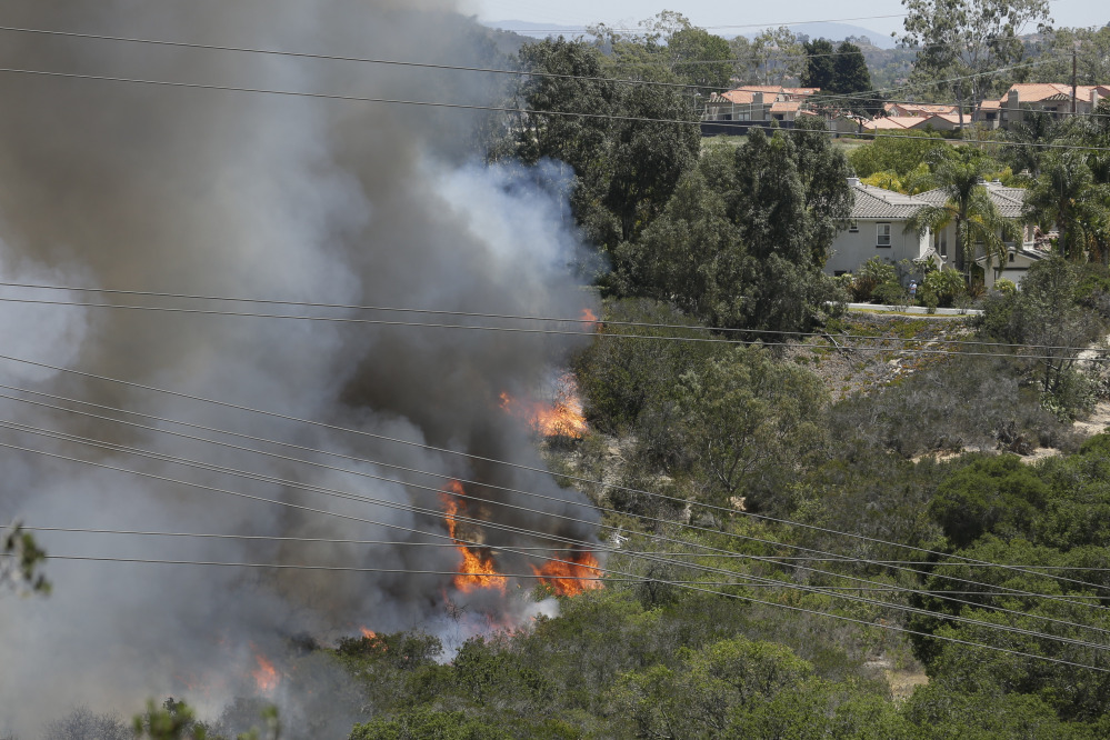 Wildfire climbs a canyon toward homes Wednesday in Carlsbad, Calif.