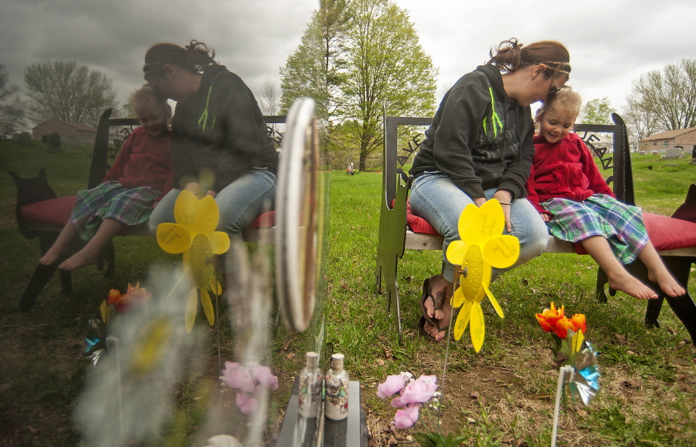 Riley Souzer, 2, cuddles with her mother, Tabitha Souzer, at the grave site of her half sister Avery Jean Lane at North Fairfield Friends Meeting House cemetery Thursday.