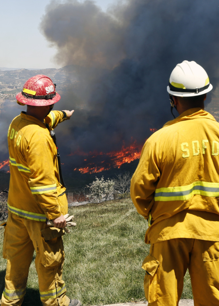 Firefighters plan their attack as a brush fire flares up, heading toward homes Thursday in San Marcos, Calif., north of San Diego.