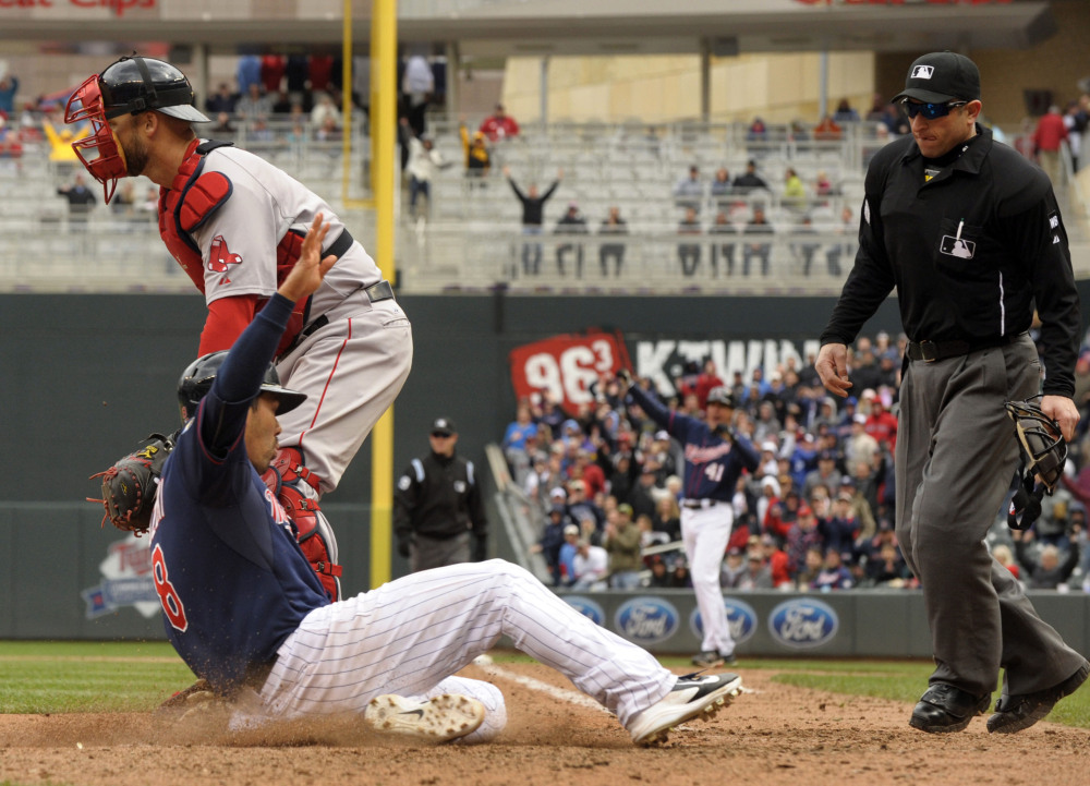 Twins catcher Kurt Suzuk slides past Red Sox catcher David Ross with the winning run in the 10th inning Thursday. Home plate umpire Chris Guccione, right, looks in to make the call. Minnesota won 4-3.