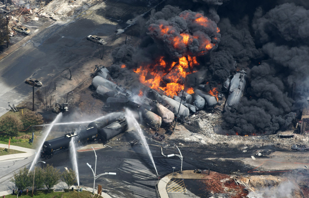 Smoke rises from flaming railway cars that were carrying crude oil after a train derailed in downtown Lac-Megantic, Quebec, in July 2013. The top executive of Central Maine and Quebec Railway said Friday that the company wants to resume oil shipments on the route by January 2016 after track safety improvements are made.
