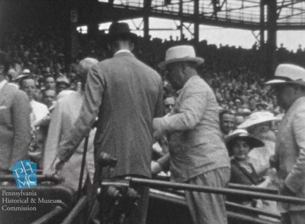 In this image taken from film shot by former Major League Baseball player Jimmie DeShong, President Franklin D. Roosevelt, center, walks to his seat with the aid of an assistant at the baseball All-Star game on July 7, 1937, at Griffith Stadium in Washington.
