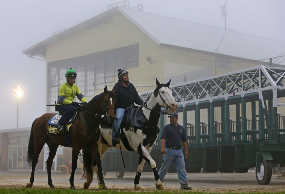 Kid Cruz, left, with exercise rider Reul Munoz aboard, walks past the grandstand after a workout under a thick layer of fog at Pimlico Race Course in Baltimore, Thursday, May 15, 2014. The Preakness Stakes horse race is scheduled to take place May 17.
