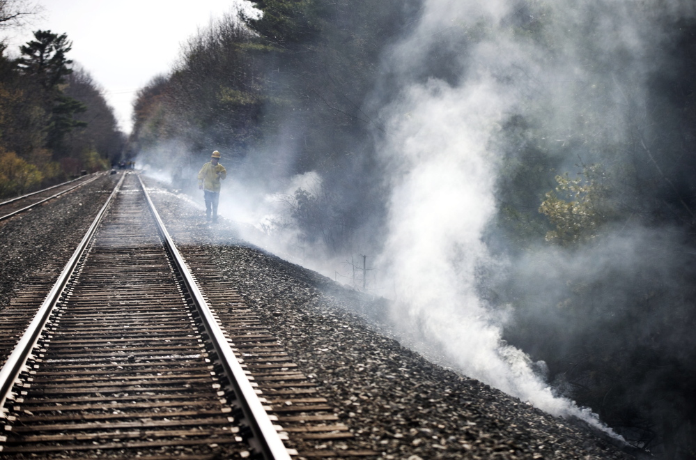 A firefighter walks near railroad tracks where a brush fire started and spread through a campground in Old Orchard Beach on May 8.