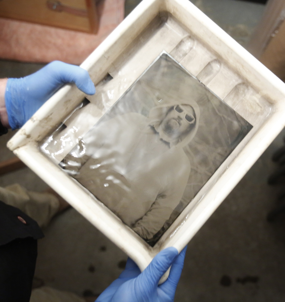 Mark Dawson watches as a tintype photograph emerges in a tray of developer.