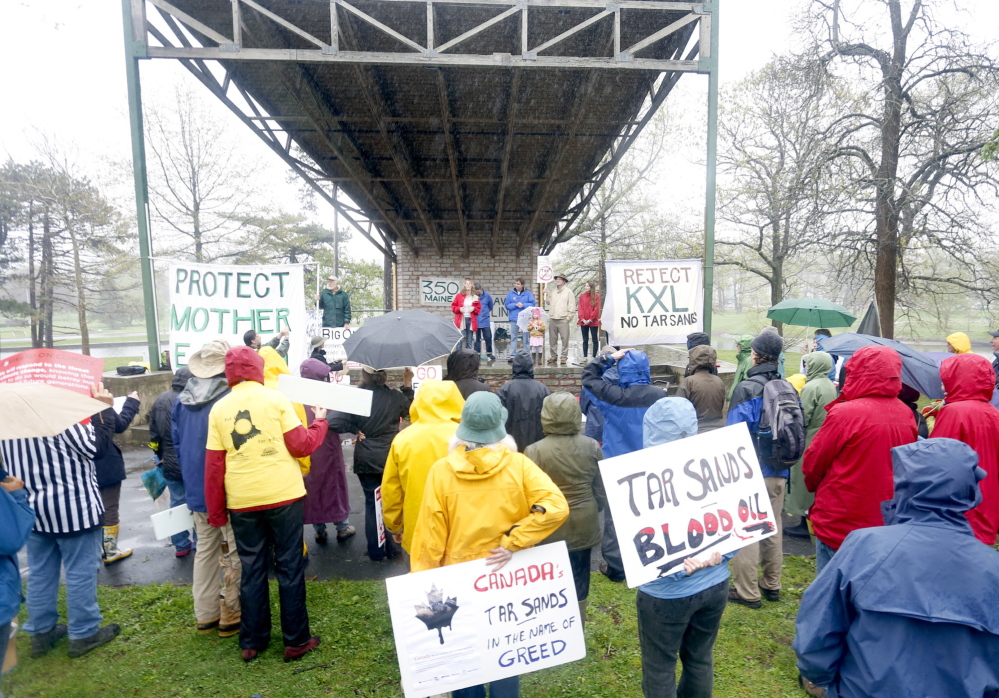 People rally in the rain Saturday in Deering Oaks to protest the extraction of oil from Canadian sand formations.