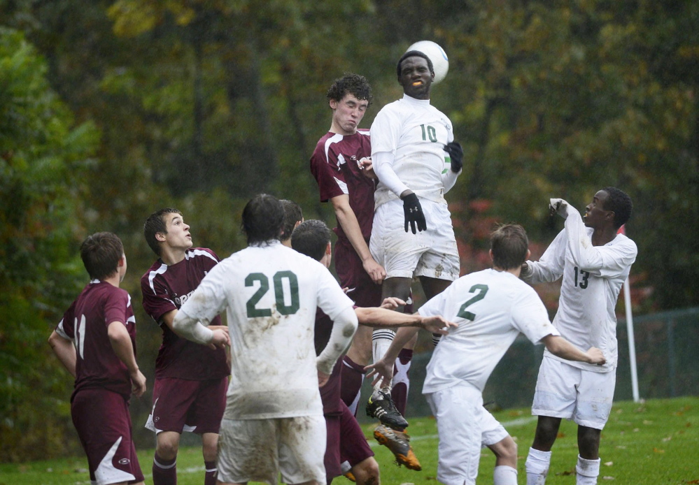 Greely’s Sam Porter and Waynflete’s Paul Runyambo go up over the the crowd trying to gain possession of the ball during soccer action in October 2012.