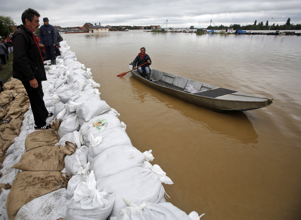 A man steers a boat along the sandbag-lined banks of the Sava River in Sremska Mitrovica, Serbia, on Saturday. Seen from the air, almost a third of nearby Bosnia resembles a lake.