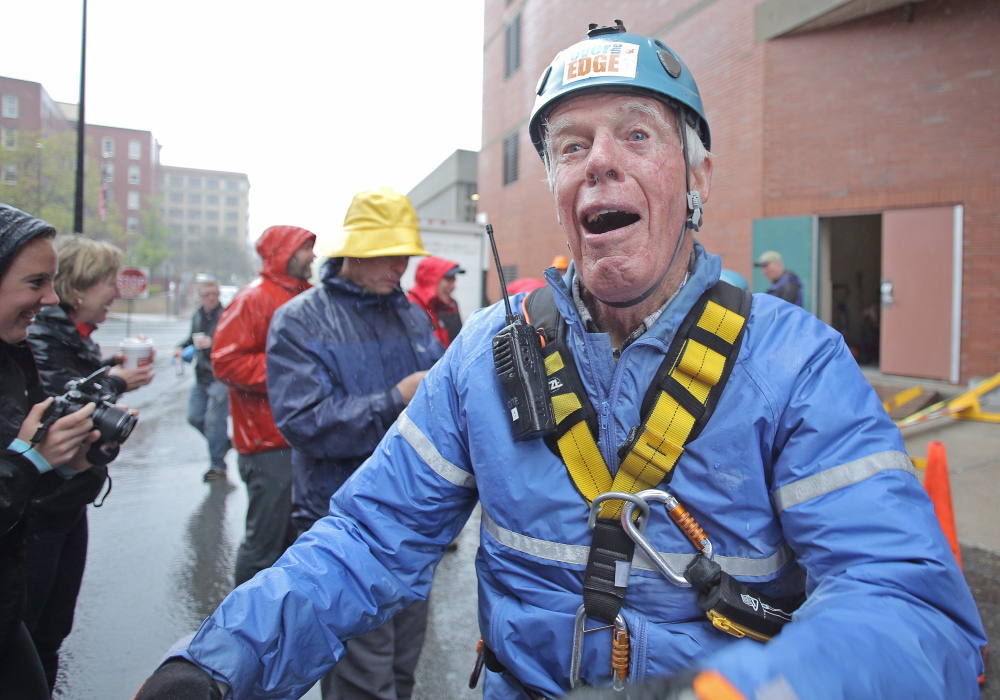 John Parker, 83, of Falmouth celebrates after rappelling down the side of One City Center in Portland as part of a fundraiser.