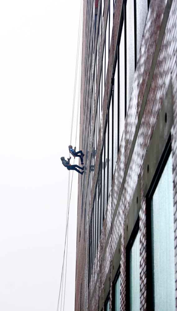 Racheal Delcourt, top, and Richard Veilleux, who both work at MaineHealth, rappel down One City Center during Rappel for Rippleffect on Saturday in Portland.