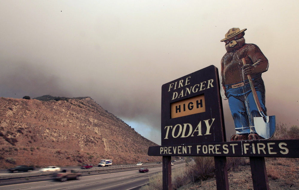 Smoke from a brush fire burning in California’s Los Padres National Forest drifts over Interstate 5 near an old Smokey Bear sign. Smokey turns 70 this summer. But instead of kicking back in retirement, the bear in bluejeans is returning to work to educate people about wildfires. Top and below, images of the new Smokey Bear from the Ad Council campaign being rolled out this month.