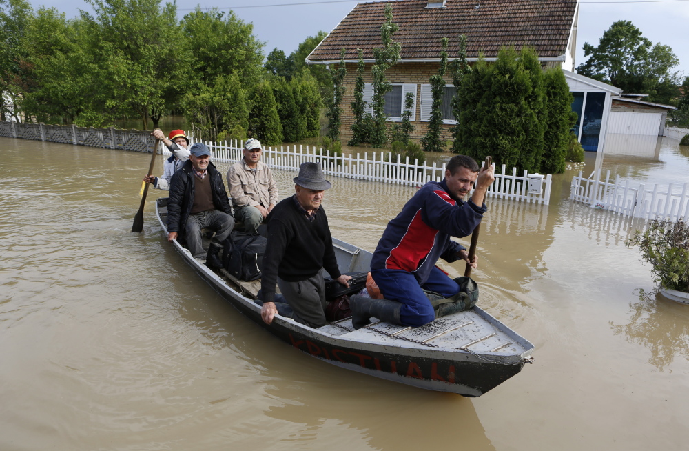 Bosnians are rescued by boat from their flooded houses Sunday in the village of Vidovice. Packed into buses, boats and helicopters, carrying nothing but a handful of belongings, tens of thousands have fled their homes in Bosnia and Serbia.