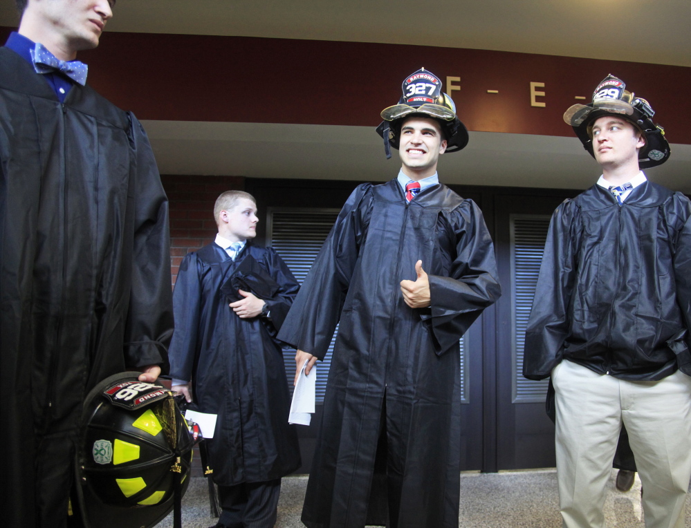 Hunter Holt, center, is already partially geared up for his career while he waits with other fire science graduates before Sunday’s ceremony.