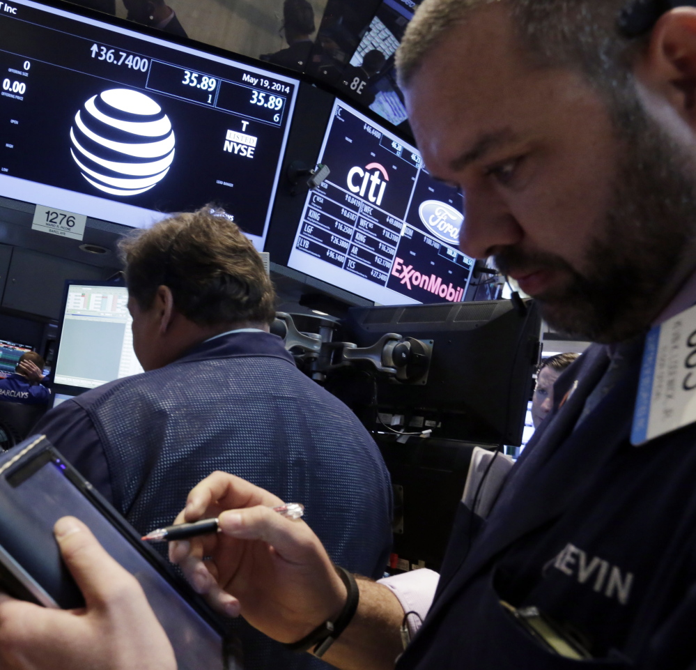 Traders gather at the post that handles AT&T on the floor of the New York Stock Exchange on Monday. AT&T Inc. announced it would buy DirecTV for $48.5 billion in cash and stock.