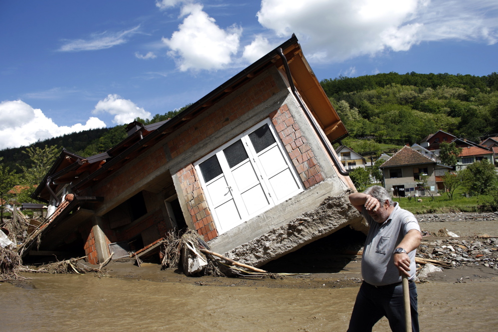 A man works near a house tilted by floods in the village of Krupanj, west of the Serbian capital of Belgrade. Communities in Serbia and Bosnia battled to protect towns and power plants from rising floodwaters and continued landslides Monday.