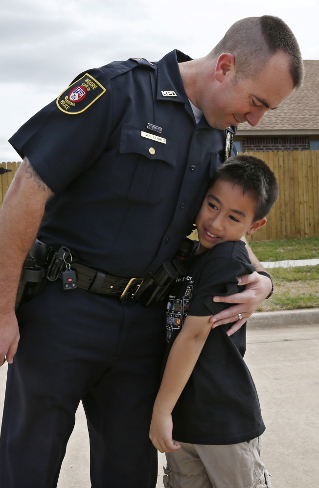 Moore police officer Travis Muehlenweg, left, hugs Kai Heuangpraseuth, as they meet in Moore, Okla. Last year, Muehlenweg was photographed pulling Heuangpraseuth from the rubble of the school. Heuagpraseuth’s mother, Jacalyn Russell, said her son has wanted to meet Muehlenweg for nearly a year.