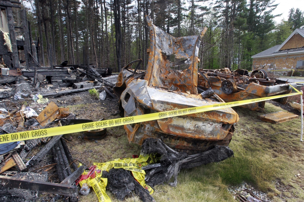 Burnt cars are seen in Brentwood, N.H., on Monday, in the front of a house where Officer Stephen Arkell was shot and killed after responding to a domestic dispute. Authorities say the house was set on fire, and leaking propane caused an explosion.