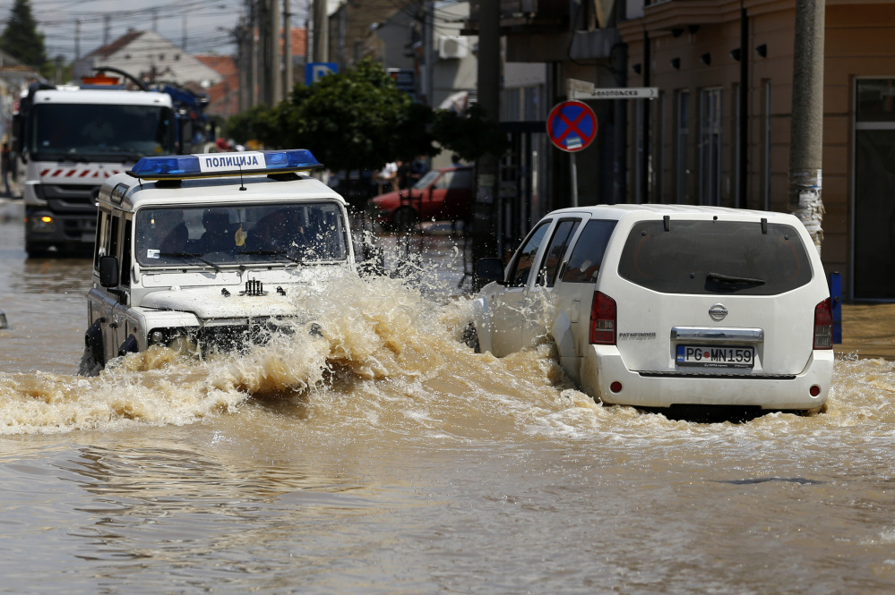 Serbian, left, and Montenegro police cars drive through a flooded street in Obrenovac, 18 miles southwest of Belgrade, Serbia, on Tuesday.