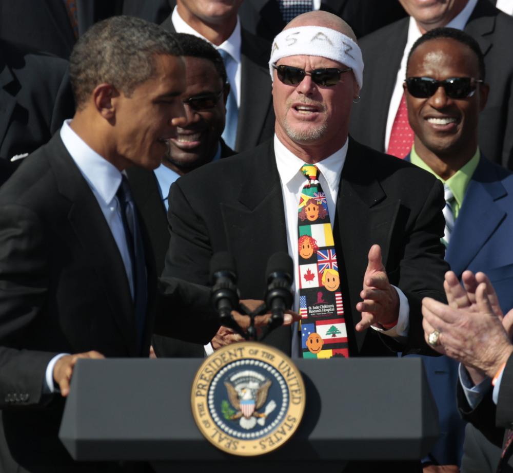 President Barack Obama, left, looks toward quarterback Jim McMahon, wearing headband, as he honors the 1985 Super Bowl XX Champion Chicago Bears football team at the White House in this 2011 photo. McMahon is among eight named plaintiffs in a lawsuit that claims the NFL illegally supplied them with risky painkillers that numbed their injuries and led to medical complications.