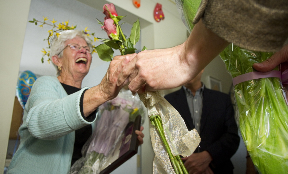 Agnes Dugas receives flowers while being honored for 18 years of volunteering at the Sagamore Health Center in Portland on Tuesday.