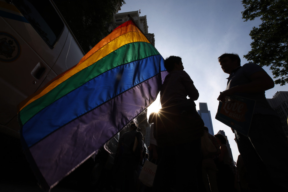 A person holds a flag during a rally at Philadelphia City Hall on Tuesday. Pennsylvania’s ban on gay marriage was overturned by a federal judge Tuesday.