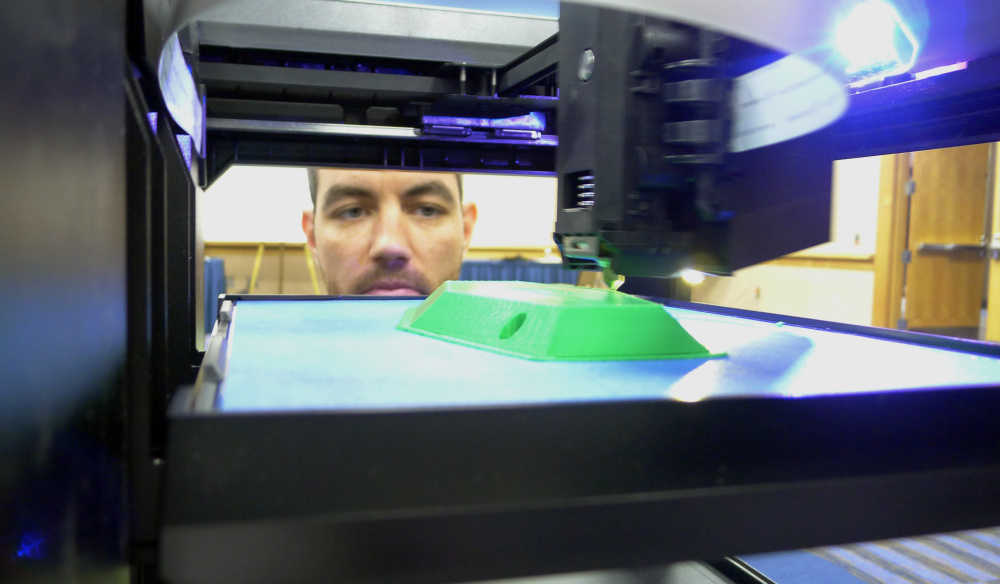 Michael Fieldson watches a 3D printer making an object during a trade show in Tampa, Fla.