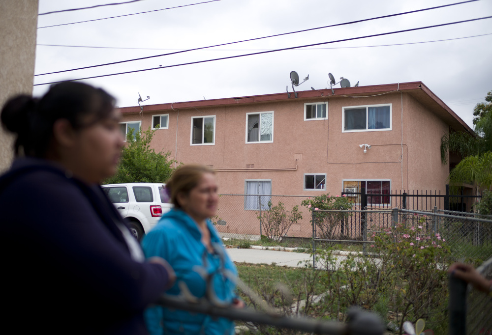 Neighbors chat Thursday near the building where Isidro Garcia lived in Bell Gardens, Calif., with a woman he is accused of kidnapping a decade ago.