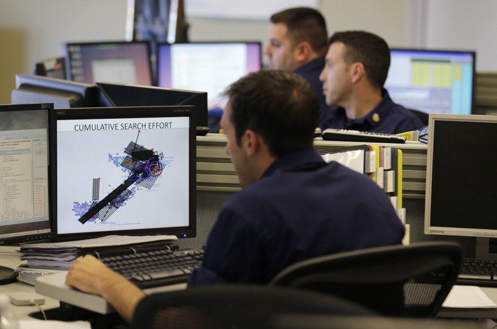 Operations unit controllers at the command center at the U.S. Coast Guard district headquarters in Boston check search pattern maps while trying to find the Cheeki Rafiki and its crew off the coast of Massachusetts.