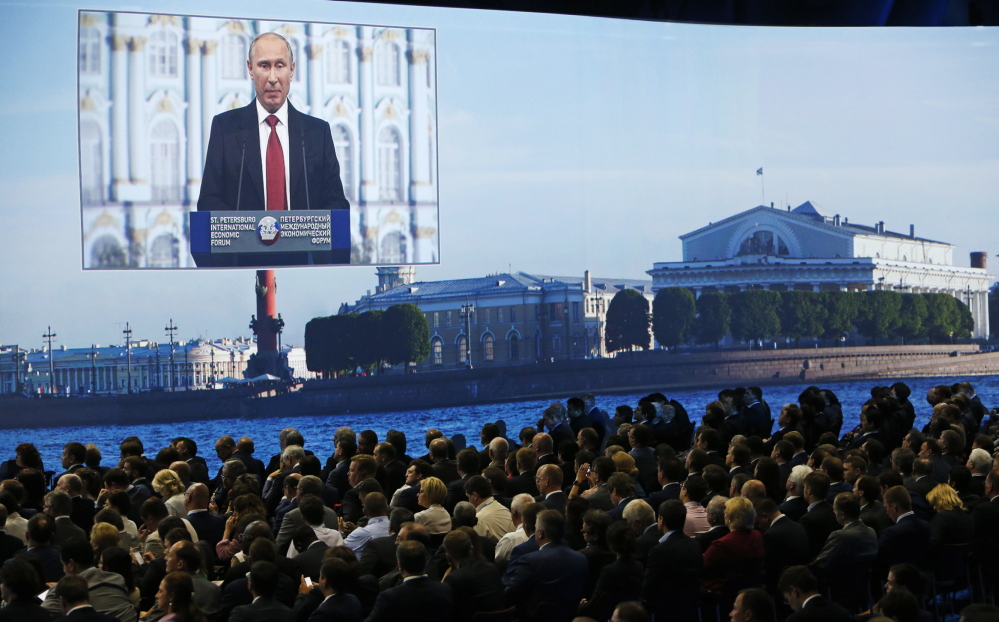 Participants listen to Russian President Vladimir Putin’s address at the St. Petersburg International Economic Forum 2014 in St. Petersburg, Russia, on Friday. Putin said Russia will “respect the choice of the Ukrainian people” in the upcoming vote.
