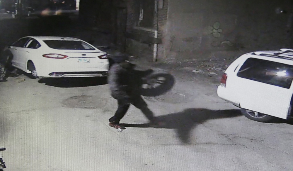 In an image from video provided by the Detroit police, car thieves take the tires off a Ford Fusion. Detroit police reported 720 carjackings last year in the city of 700,000 people.